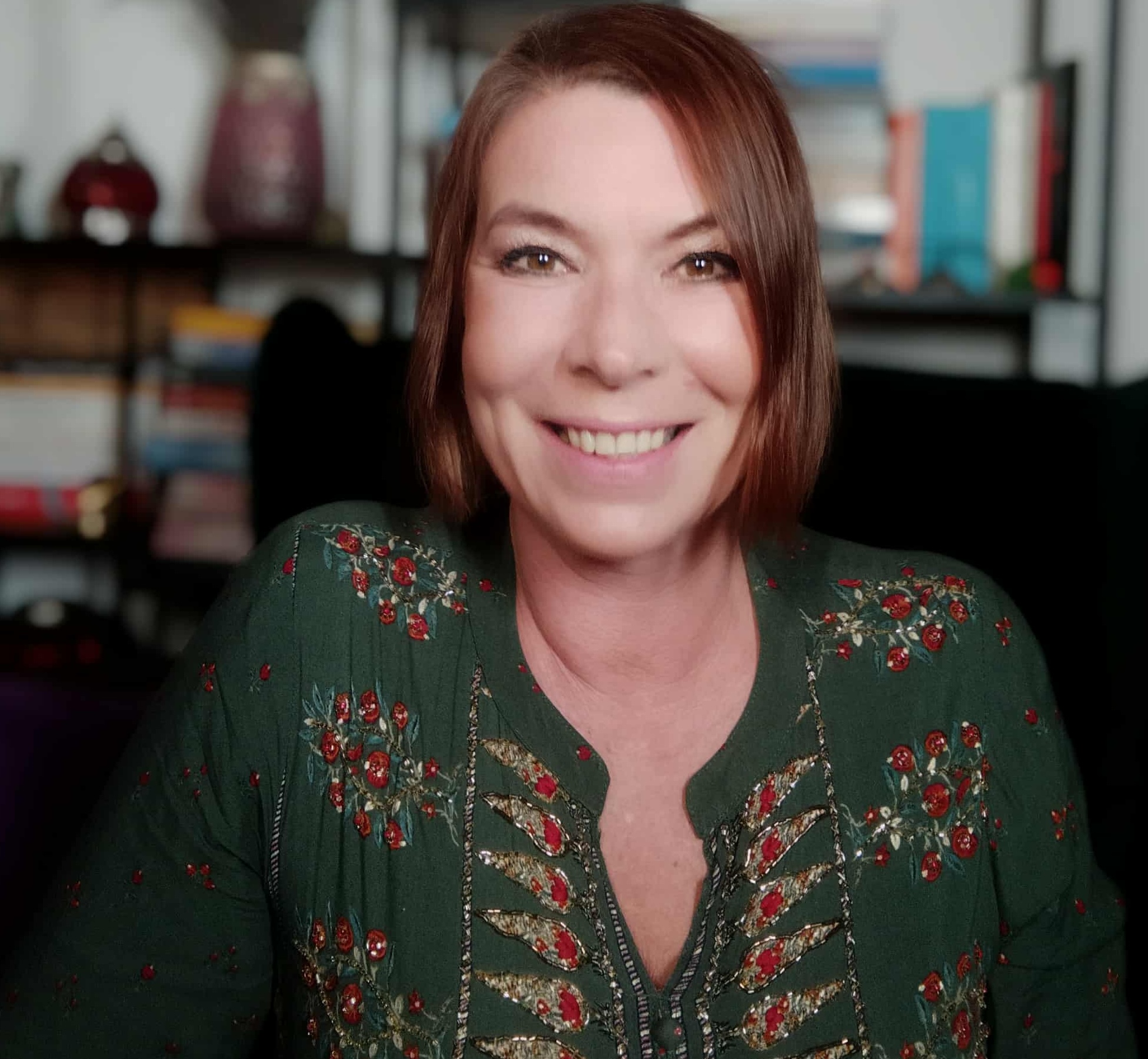 Mitglied vom FrauenRaum Netzwerk Valentina Beata Kobluk lächelt in die Kamera und trägt dabei ein grünes Kleid mit rot und goldenen Verzierungen.