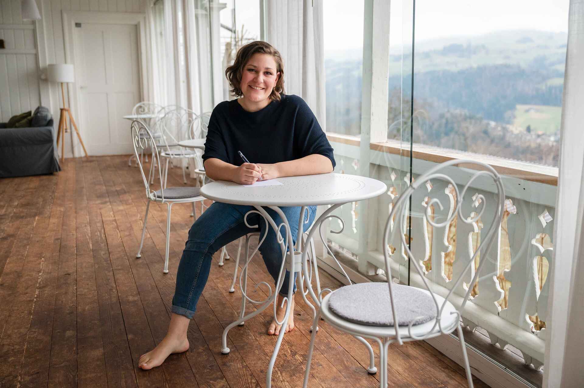 Mitglied vom FrauenRaum Netzwerk Anja Herren von KaJa Familienberatung sitzt an einem weissen Tisch und lächelt in die Kamera.