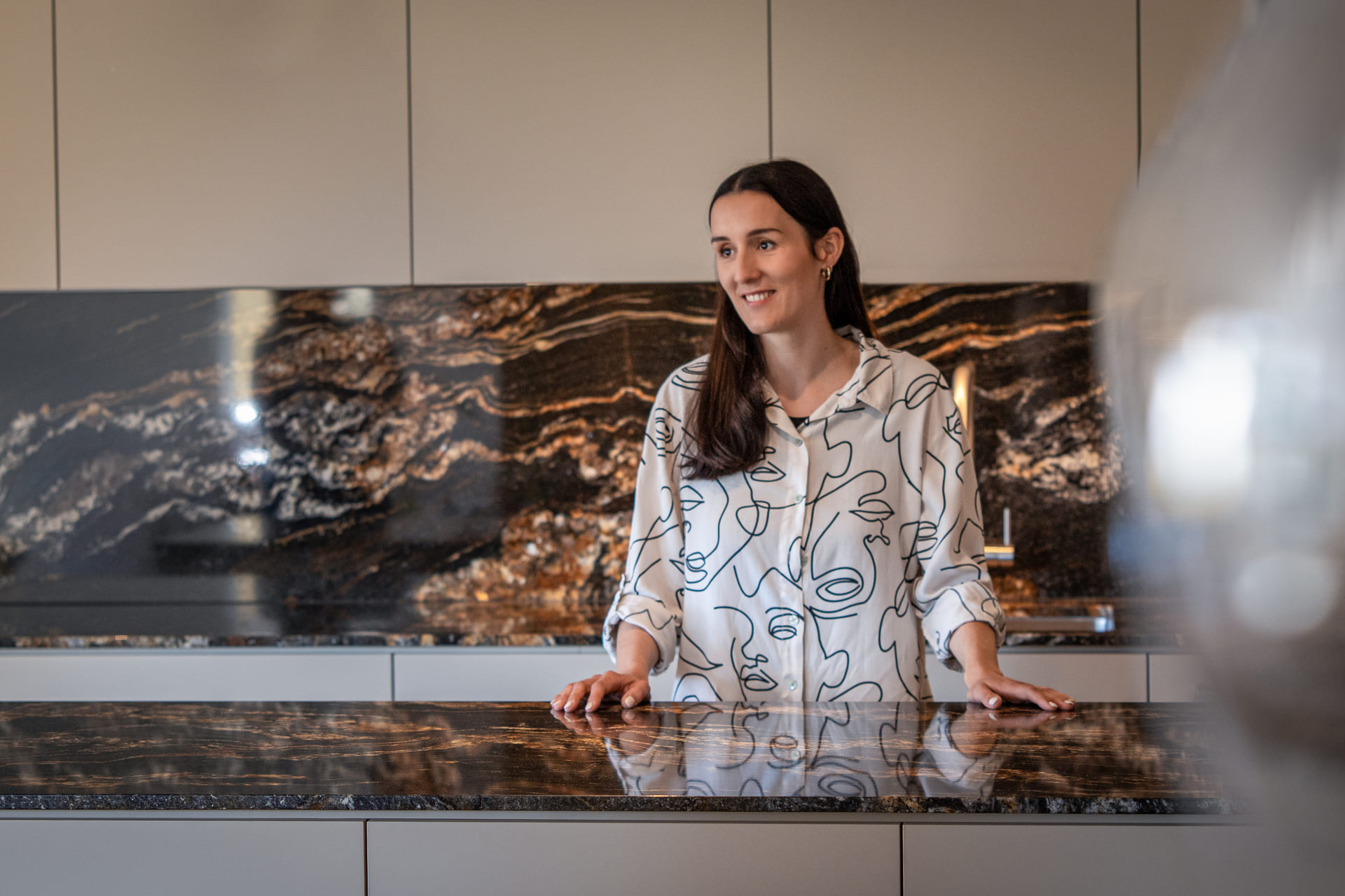 Mitglied vom FrauenRaum Netzwerk Atelier Céline Innenarchitektur und Design steht in einer grauen Küche und schaut in die Ferne.