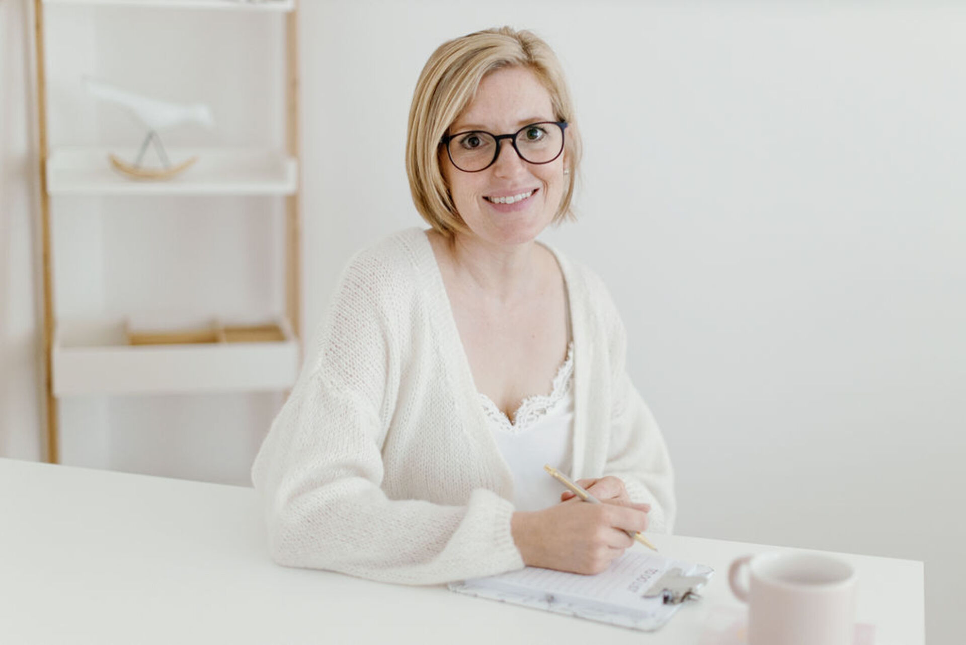 Mitglied vom FrauenRaum Netzwerk Nathalie Tehrani von natürlich gesund lächelt in die Kamera, während sie ein Bleistift in der Hand hält um sich Notizen aufzuschreiben.