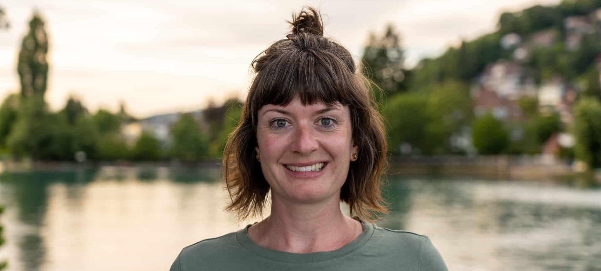 FrauenRaum Netzwerk Mitglied Pia Kober von Kobkom lächelt in die Kamera, hinter ihr ist der Thhunersee unscharf zu erkennen.