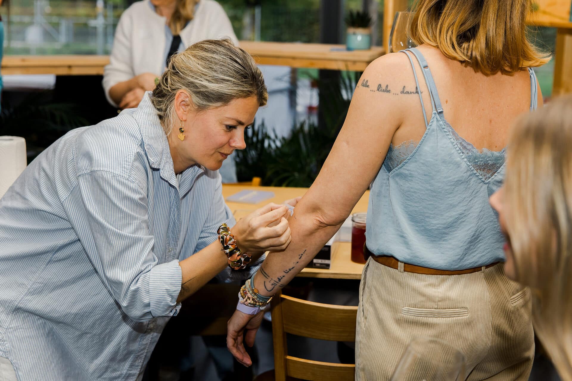 Die Tätowiererin Sylvie von Sylvie mit Herz klebt gerade ein Design zum tätowieren auf die Hand einer Frau.