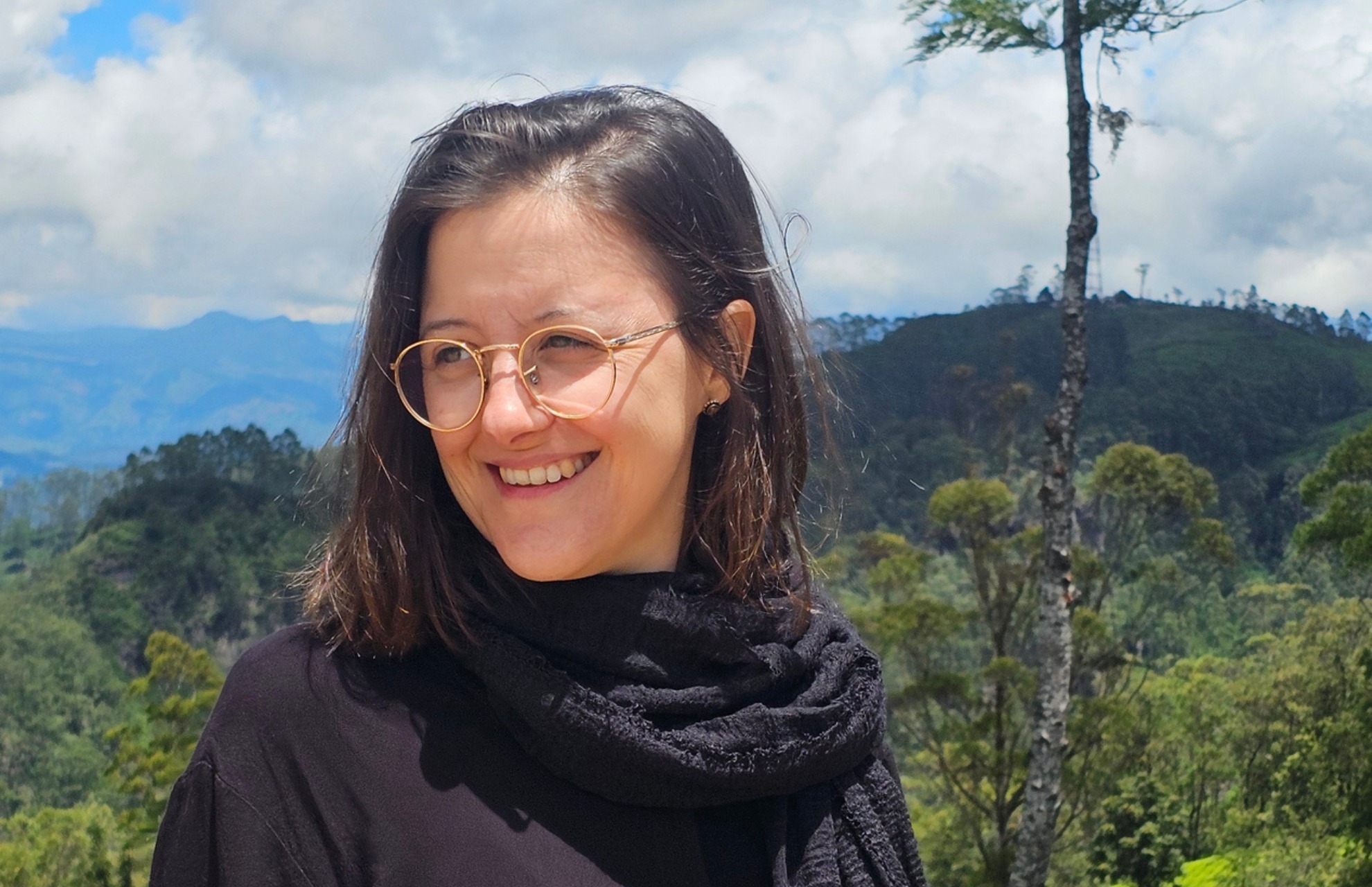 Sarah Zimmermann steht in der Natur von Sri Lanka und lächelt in die Ferne.